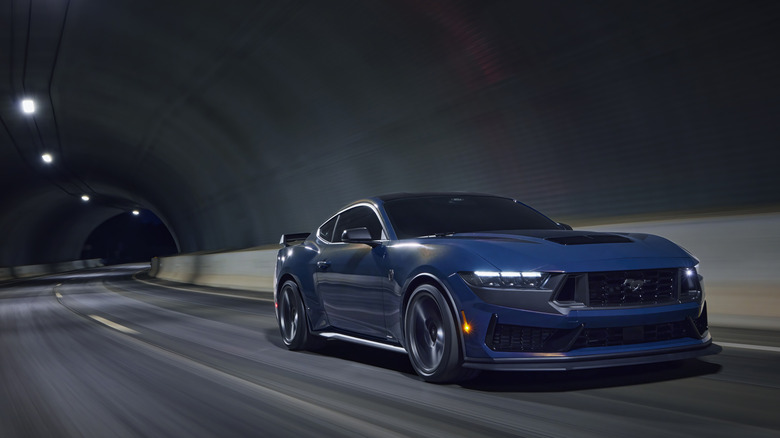 2025 Ford Mustang Dark Horse driving at speed in a tunnel, low-profile front 3/4 view