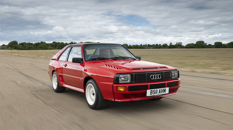 Red Audi Sport Quattro front 3/4 view driving on an empty track