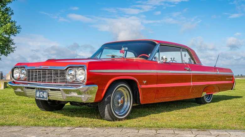 Red Chevrolet Impala parked on grass