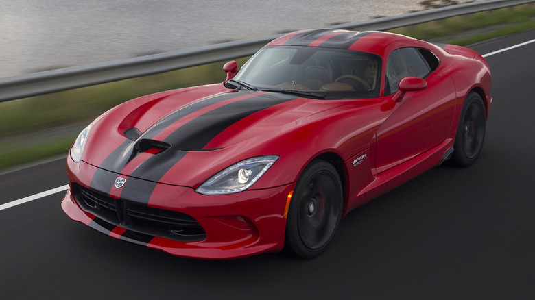 Red Dodge Viper driving in front of guard rail