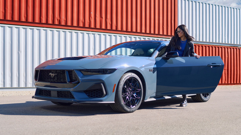 Powder blue Ford Mustang parked in front of storage containers