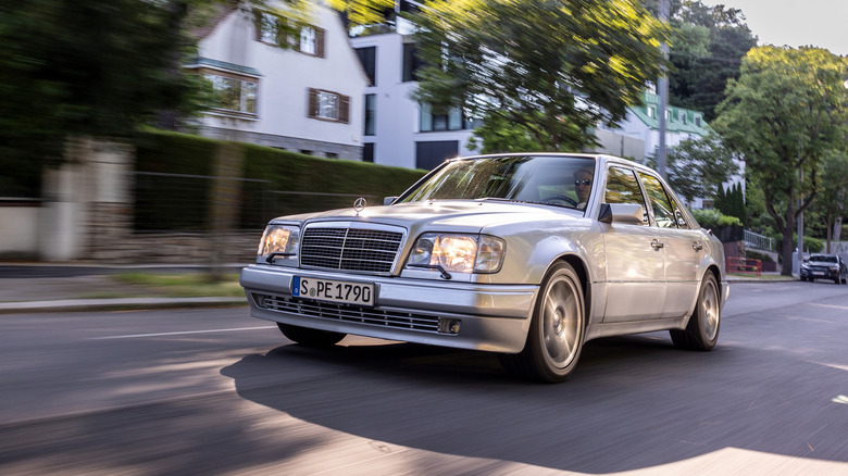 Silver metallic Mercedes-Benz E-Class W124 driving on urban street