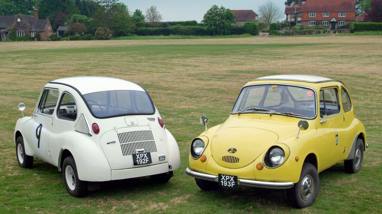 Two Subaru 360 micro cars parked on meadow