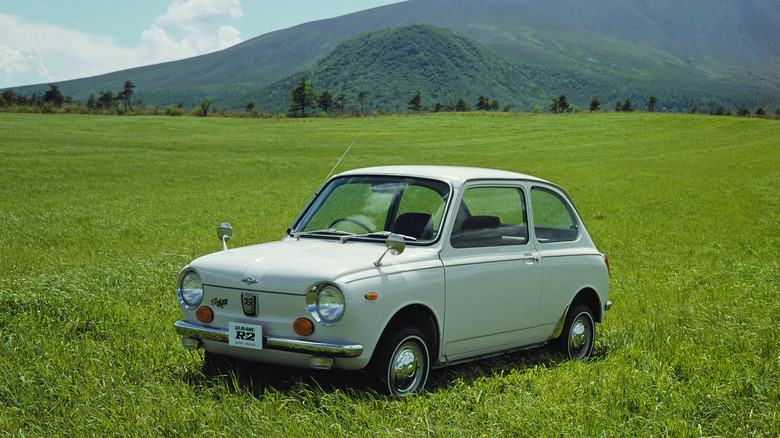 1969 Subaru R-2 parked on meadow with mountains in the background