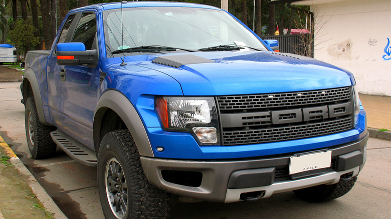 A blue 2011 Ford Raptor parked on a city street