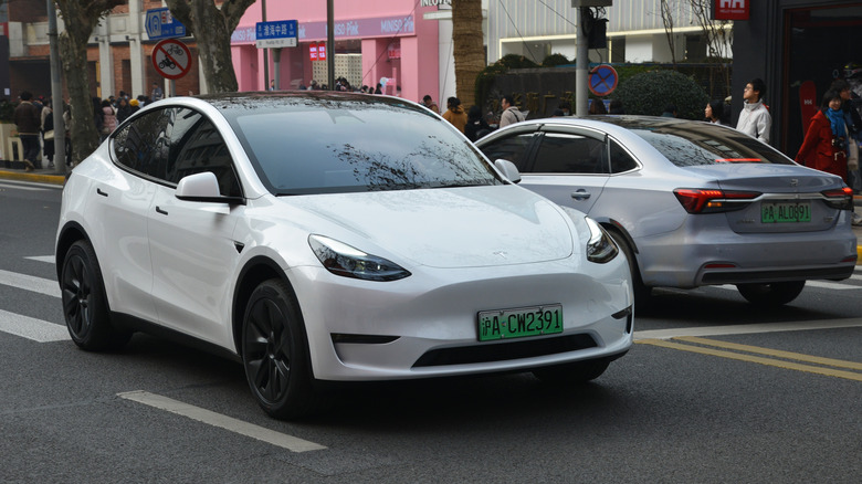 A white Tesla car driving on the road