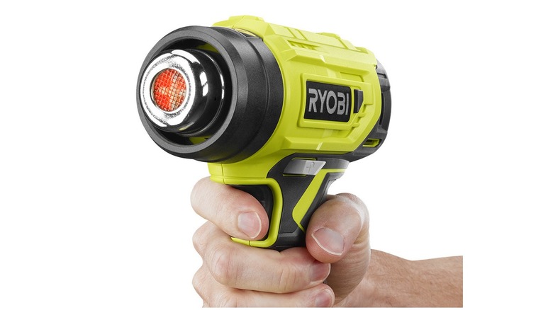 Hand holding a green and black heat gun