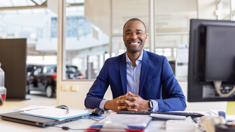 car salesman sitting at desk