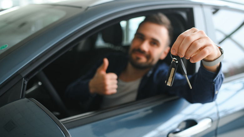 man giving thumbs up while sitting in drivers seat