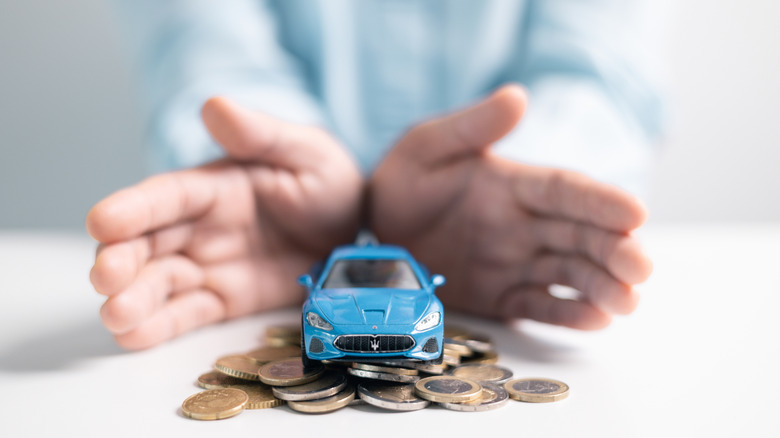 a car figurine sitting on pile of coins