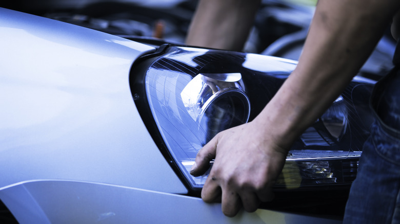 Person holding onto a headlight