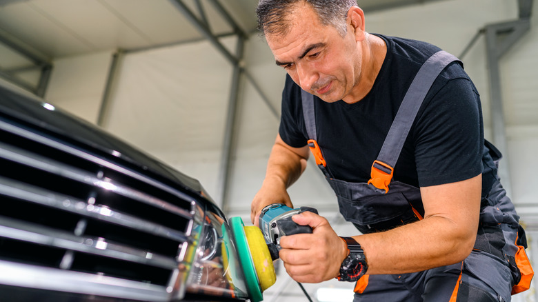 Person using an orbital sander on a headlight