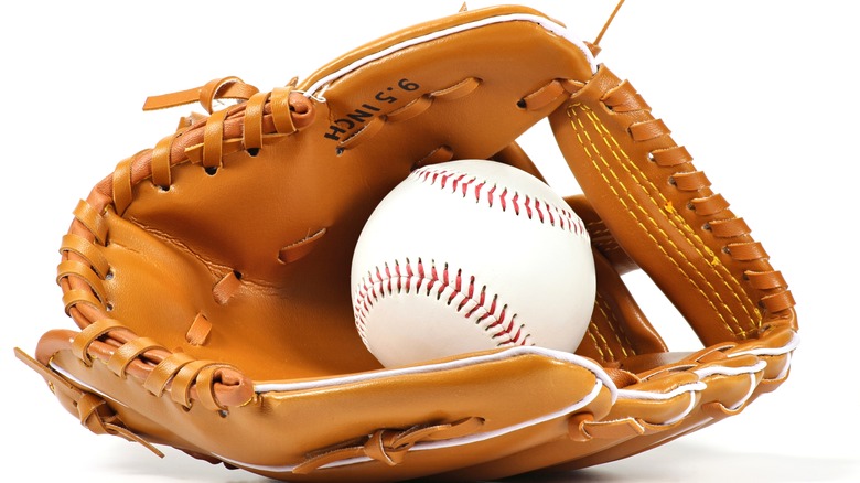 A baseball player holding a ball and glove behind their back