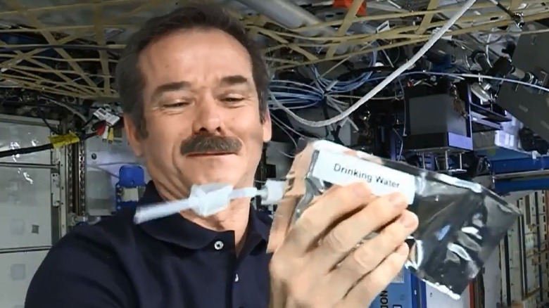 Chris Hadfield holds bag of drinking water