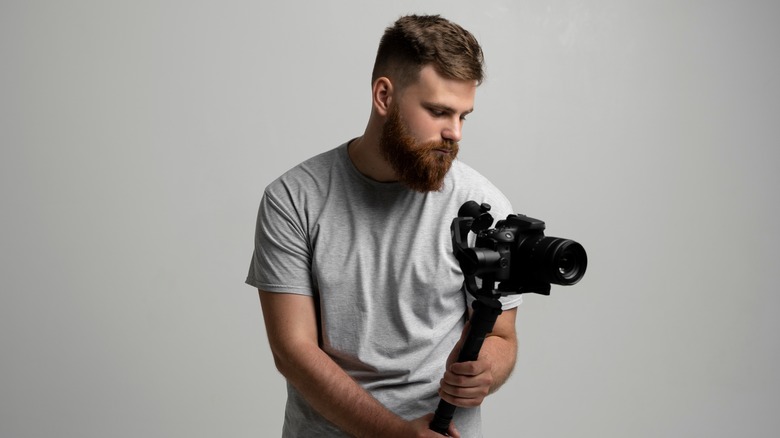 Man holding digital camera on monopod