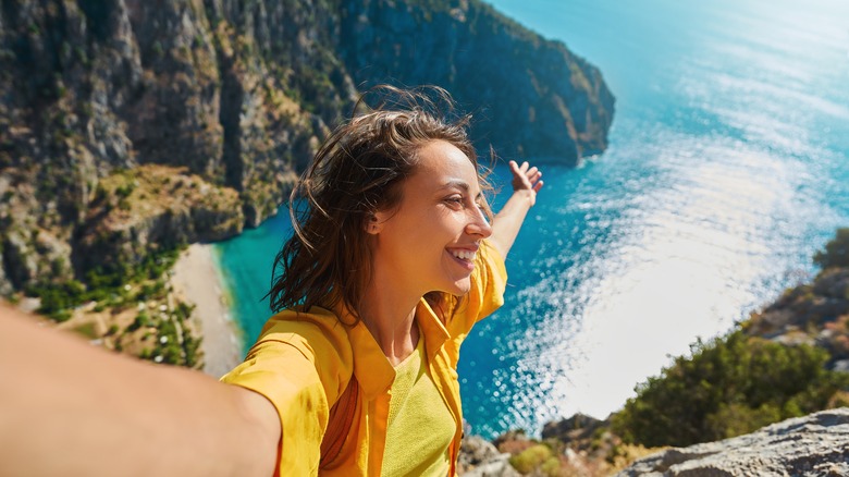 Smiling woman overlooking water from cliff