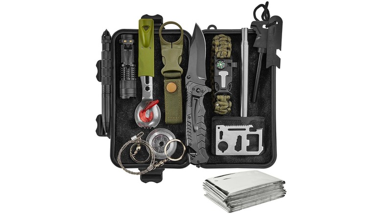 Survival kit with a knife, folded emergency blanket, compass, spoon, flashlight, and other items