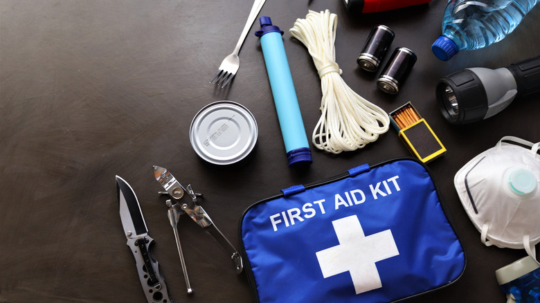 Blue first aid kit with medical supplies, can opener, knife, rope, matches, and other survival gear