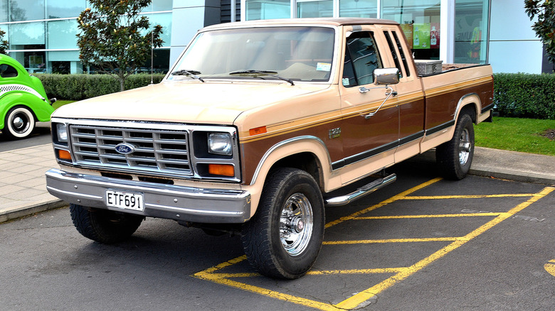 A brown and tan 1986 Ford F-250 in a parking space