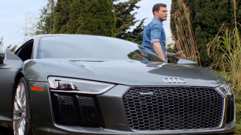 Jamie Dornan standing by his Audi R8 in Fifty Shades Freed