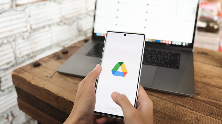 woman holding smartphone with Google Drive logo on screen