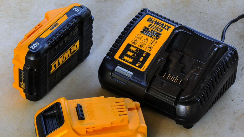 Two DeWalt 20V batteries beside a DeWalt charger.