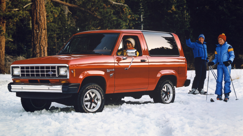 1984 Ford Bronco II parked in the snow with skiers