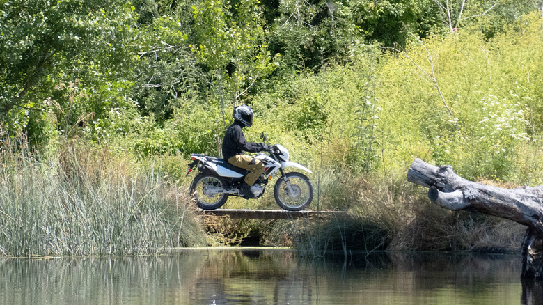 2023 Honda XR150L crossing a bridge on a ranch pond