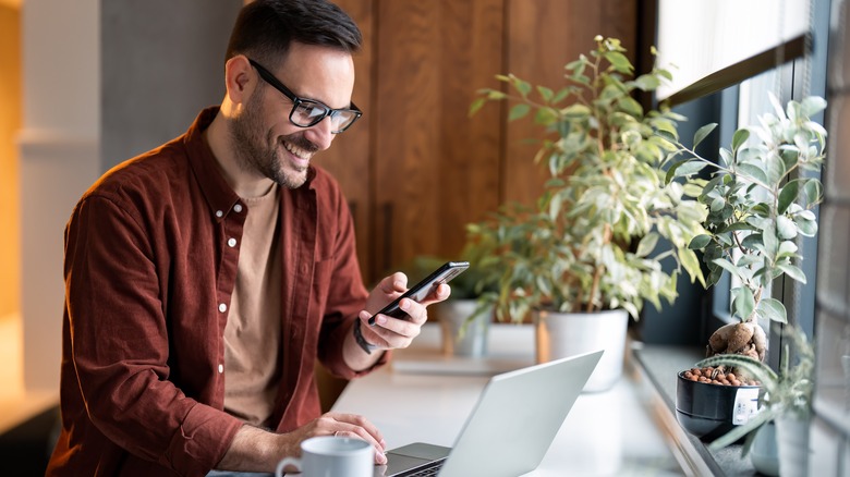 man using smartphone and laptop