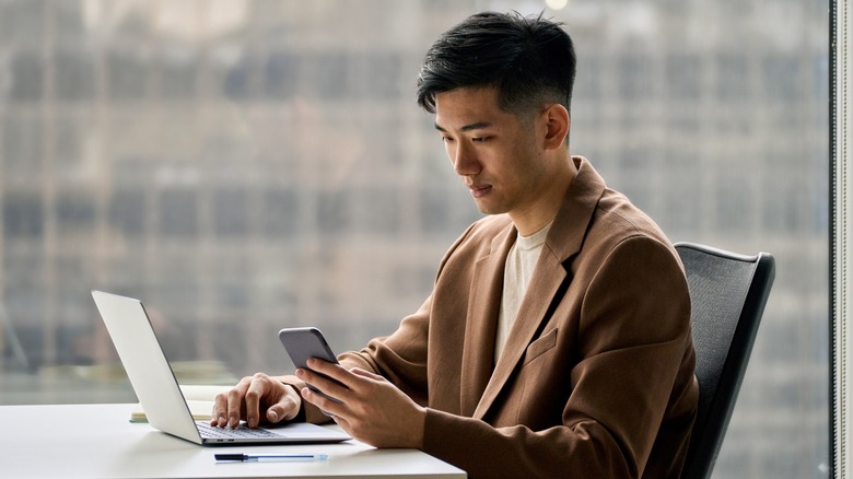 man shopping online with phone and laptop