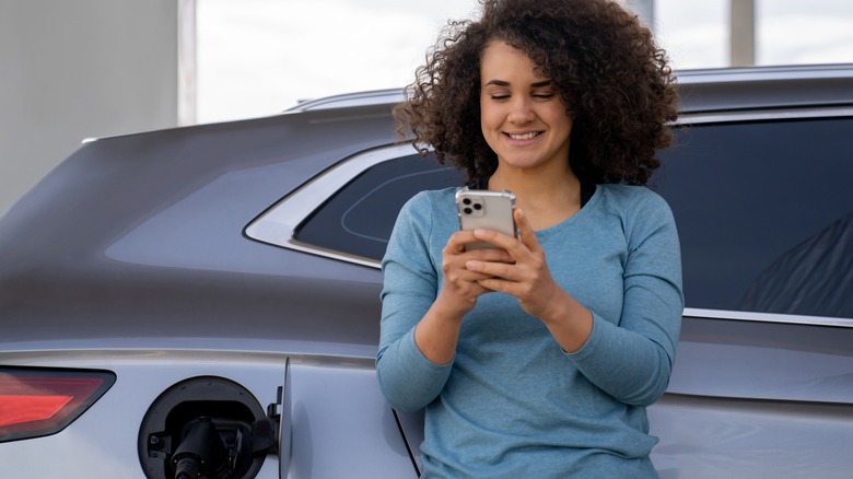 Woman on phone leaning on car