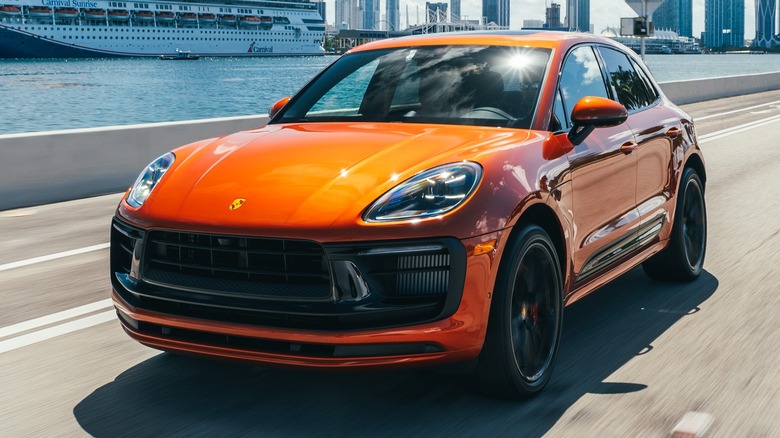 Orange Porsche Macan GTS driving by water