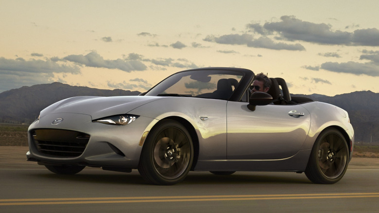 Front 3/4 view of Mazda MX-5 Miata driving at sunset