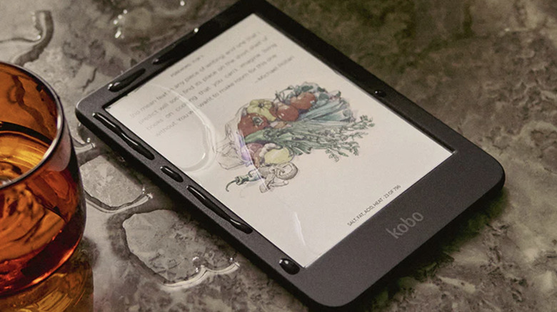 A Kobo Clara Colour e-reader placed next to a glass of water that spilled a little water on the display