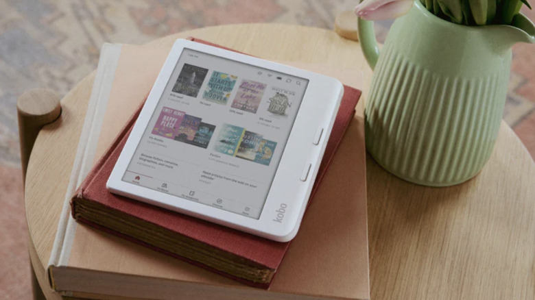 A Kobo Libra Colour e-reader placed atop a coffee table on books and beside a vase