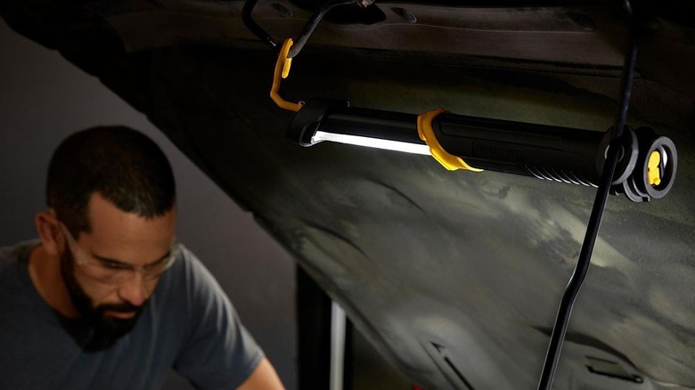 Man working under car hood with Braun shop light shining down