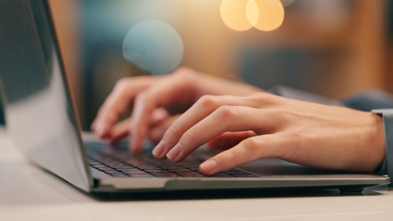 Close up picture of a woman's hands typing on a laptop