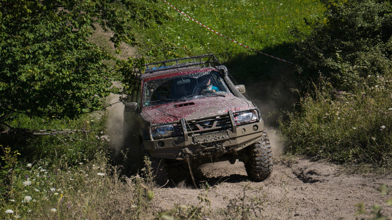 A person drives an SUV on an off-road track.