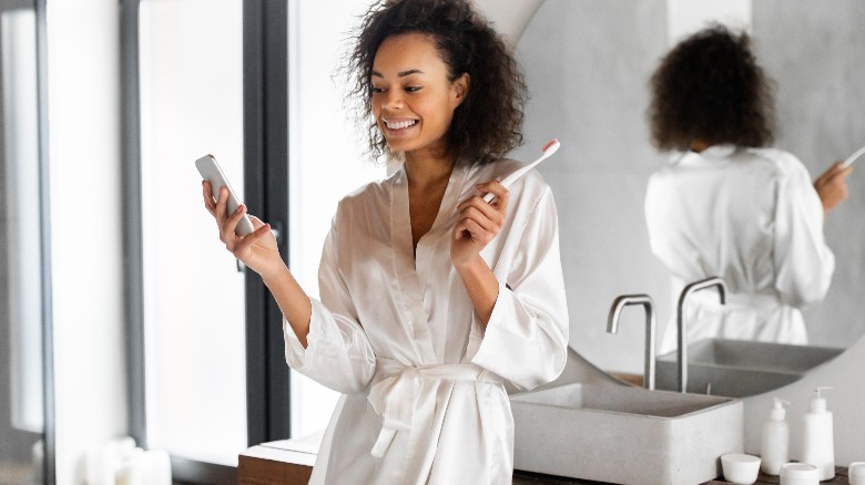 woman holding a toothbrush and phone