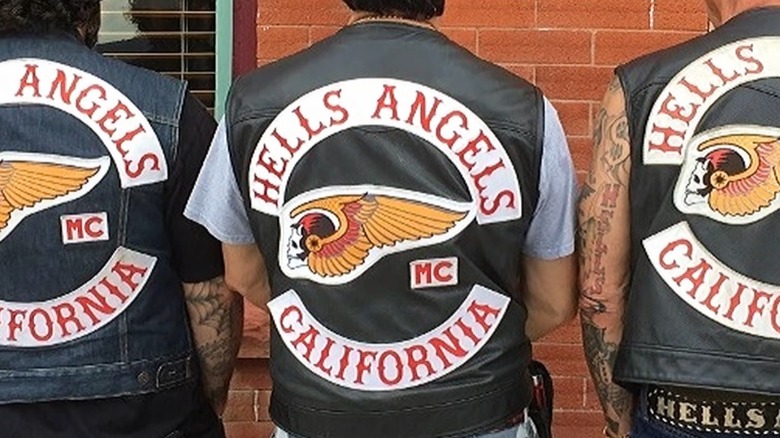 Hells Angels members with backs to camera showing off their vest insignia.