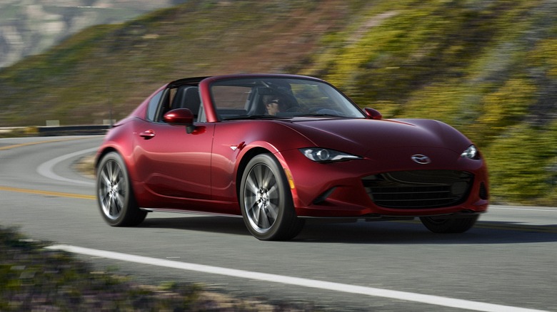 Front quarter view of red Mazda MX5 Miata driving along a mountain road