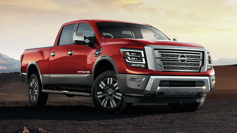 Front quarter view of red Nissan Titan parked on sandy terrain