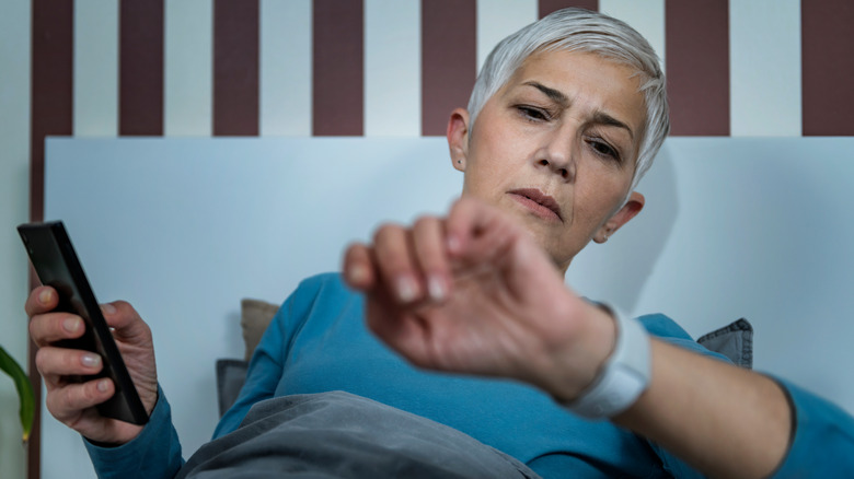 person checking smartwatch in bed