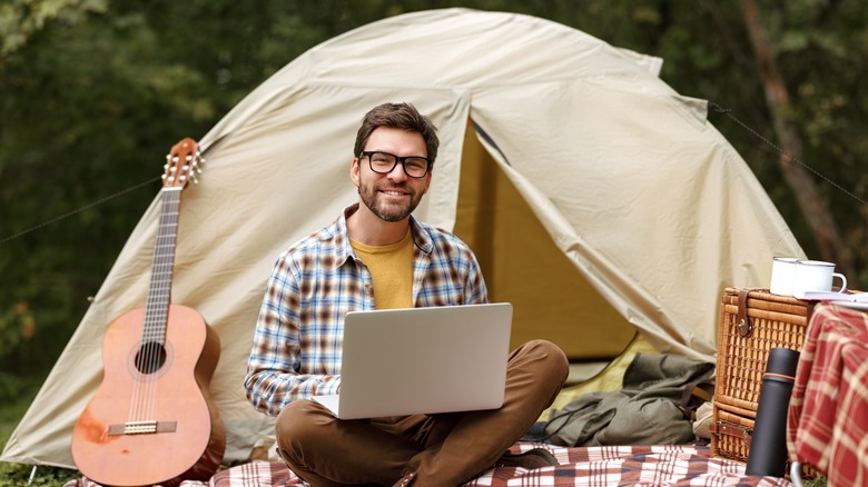 Young man using a laptop while camping