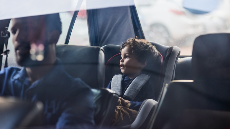 Mother strapping baby into car seat