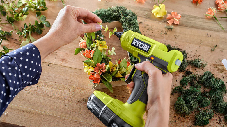 Woman using glue gun to glue fake plant