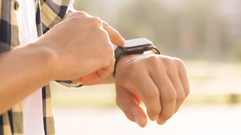 man tapping smartwatch outdoors