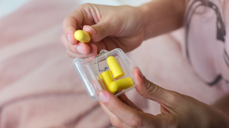 person putting earplugs bag into case