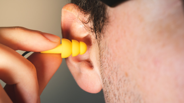 man putting on yellow earplugs