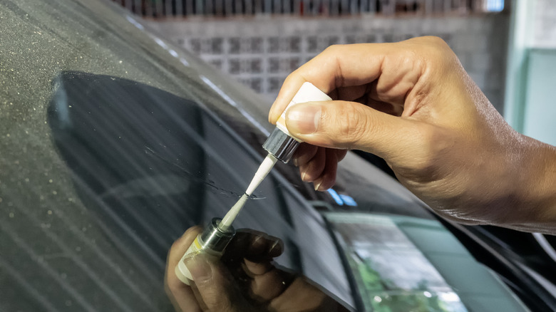 hand applying glue to cracked windshield